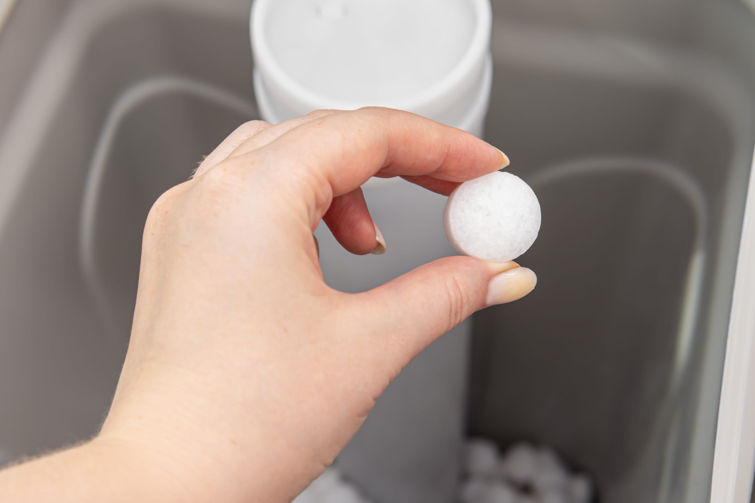Hand Holding Salt Pellet in Water Softener System from Salt Delivery Services