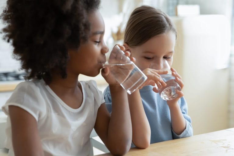 Two girls drink clean, clear water.