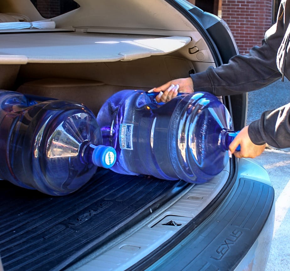 Someone put full jugs of Texas Water House water in the back of a vehicle.