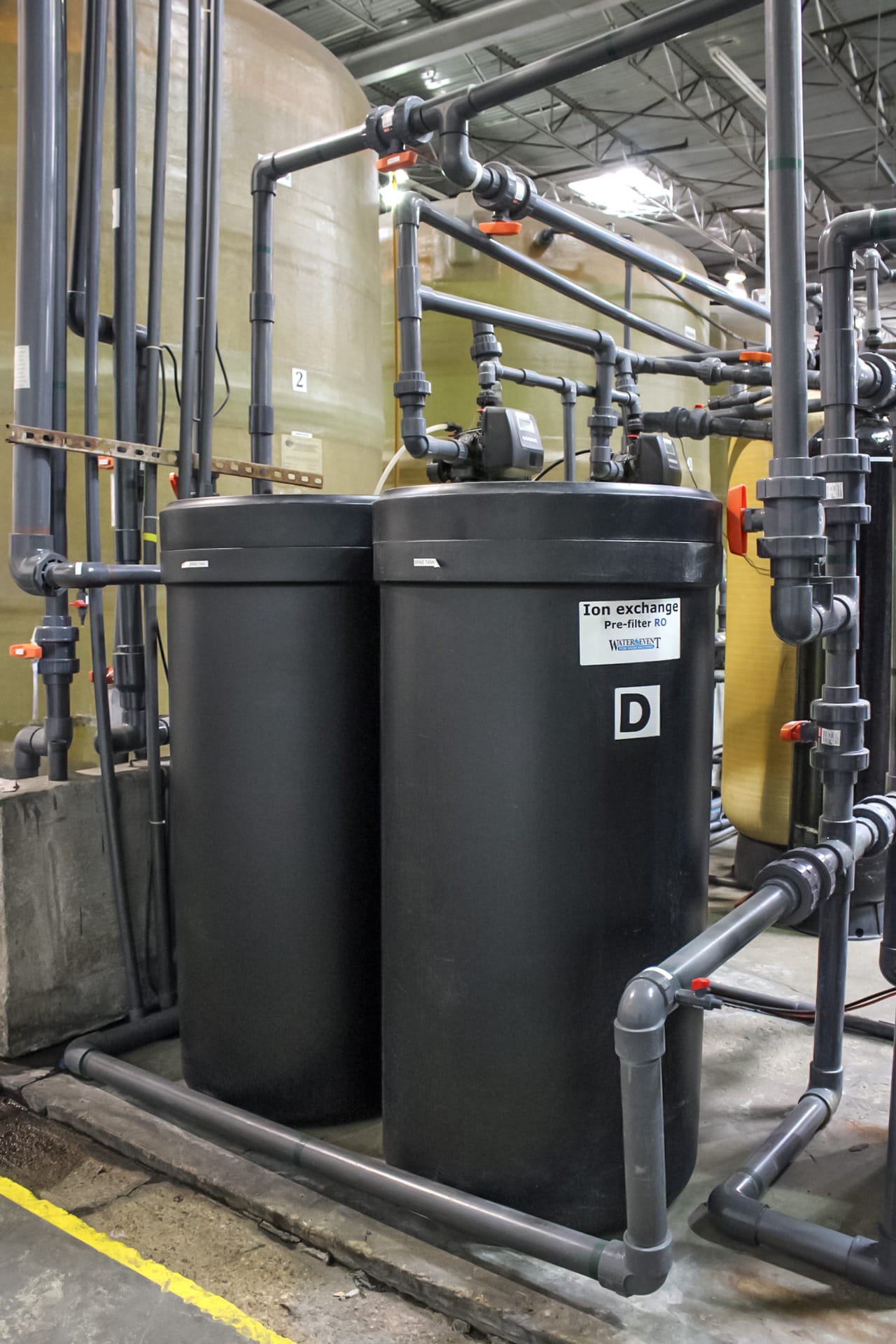 Two black water filtration systems with piping coming out of them.