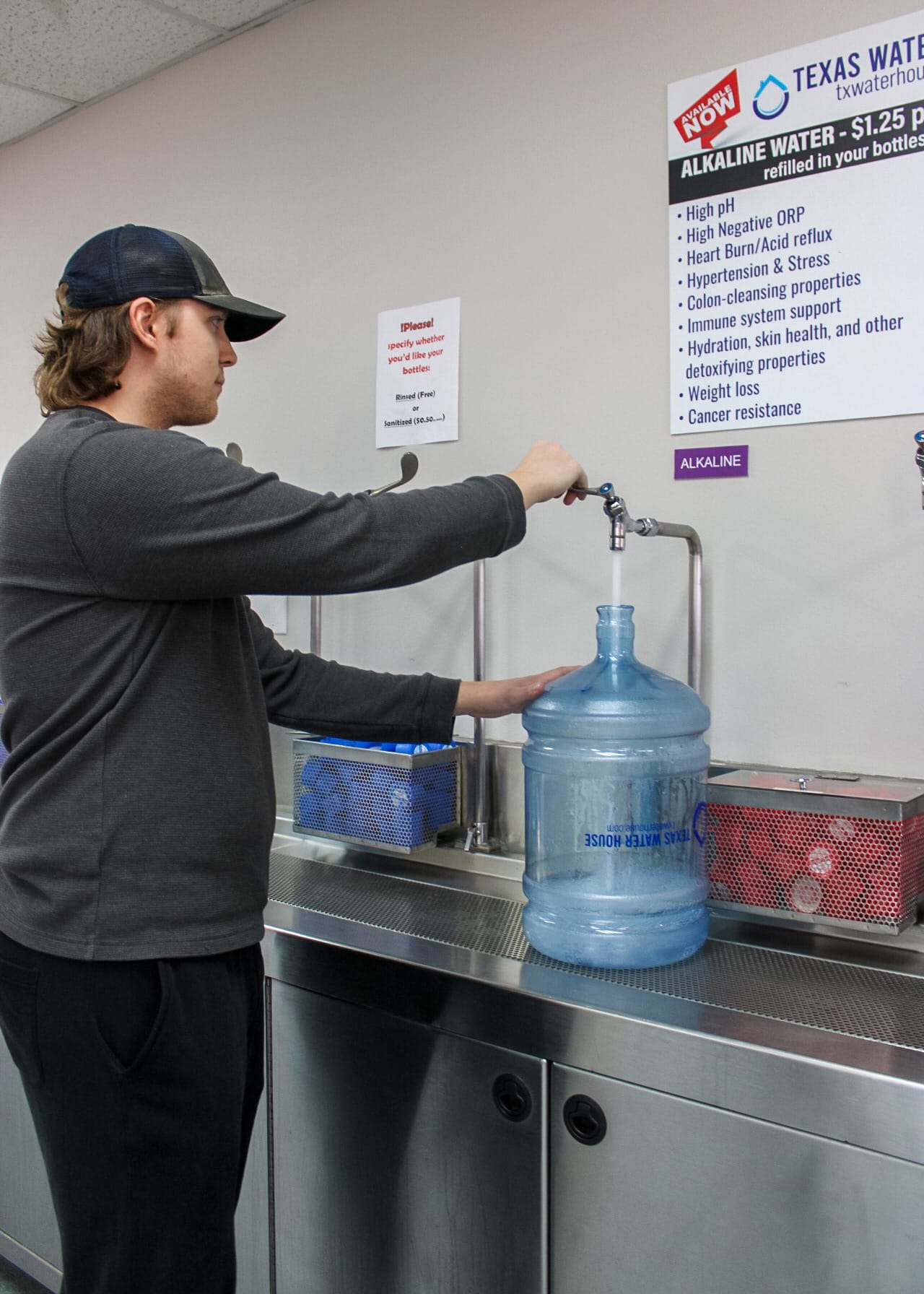Someone filling up a large water jug in Water Texas House's filling station.