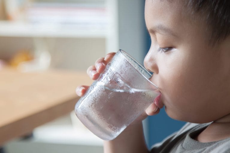 A child drinking water from a glass.